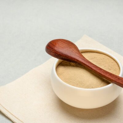 Ceramic bowl containing ashwagandha powder, with a wooden spoon on top